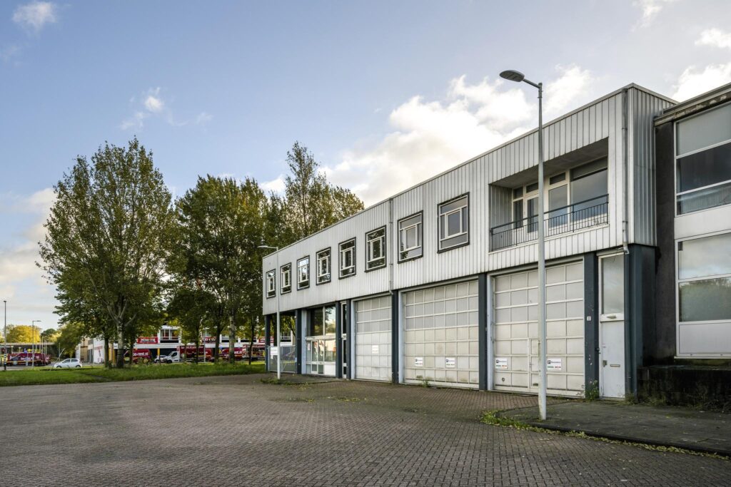 Industrial building with office units on Van der Madeweg, featuring large garage doors and a paved forecourt.